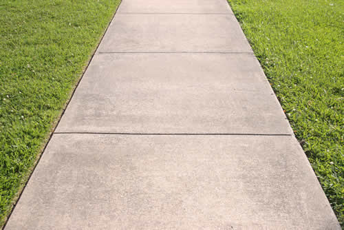 Concrete walkway with grass on each side of it